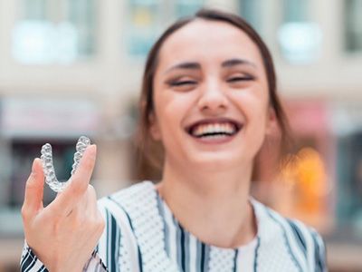 Woman enjoying a day on the town and holding up her Invisalign aligner