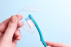 Close up of patient brushing their Invisalign tray