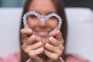 Woman holding her Invisalign so they form a heart