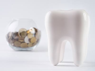 Plastic tooth next to jar of coins