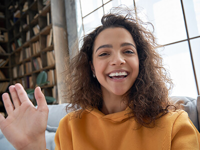 Person smiling and waving while video chatting with a friend