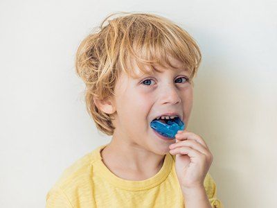 Boy putting blue mouthguard on his teeth