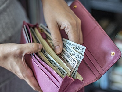 Person pulling dollar bills out of their wallet