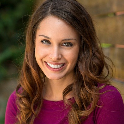 Woman in magenta blouse smiling after Invisalign in Fort Worth