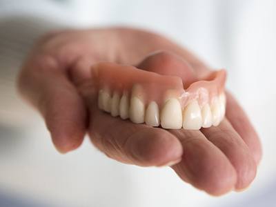 Hand holding a full upper denture