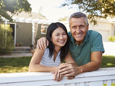 Husband and wife smiling in front of their house