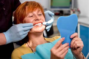 Woman in dental chair admiring her smile in mirror