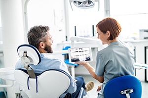 Smiling dentist and patient reviewing X-ray