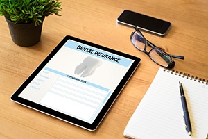 Dental insurance form on tablet on desk with notepad
