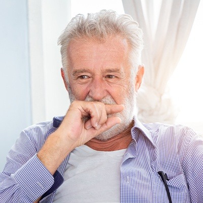 Man with beard covering his smile with his hand