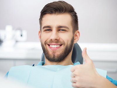 Man in dental chair giving thumbs up