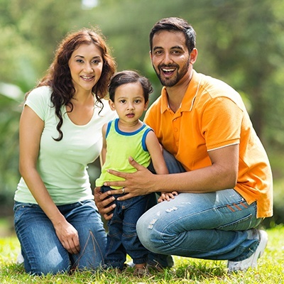 Family of three smiling outdoors after visiting family dentist in Fort Worth