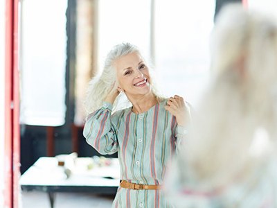Woman smiling while checking out her outfit in a mirror