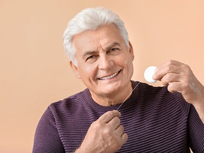 Man smiling and holding dental floss