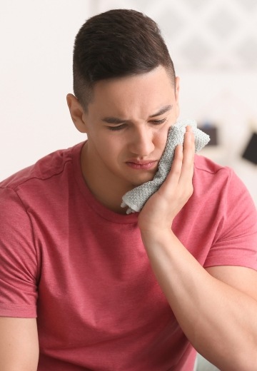 Teen boy in pain holding cold compress to his cheek