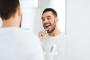 Man smiling while brushing his teeth