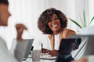 Woman smiling while taking notes during meeting