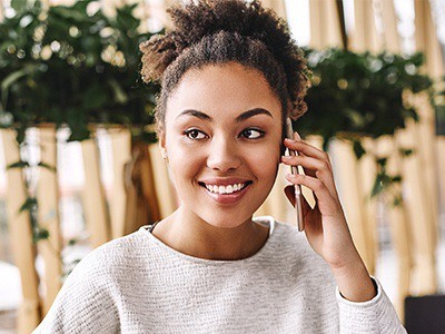 Smiling young woman with straight teeth, calling on her cell phone