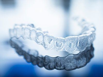 Closeup of a clear Invisalign aligner on a reflective background