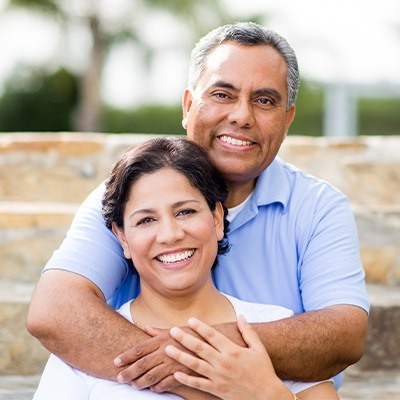 Husband hugging wife after replacing missing teeth in Fort Worth