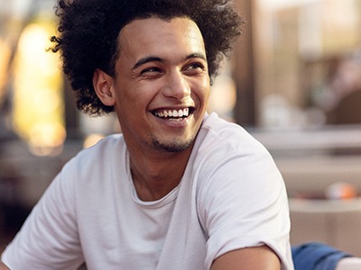 Person sitting and smiling with Invisalign aligners in Fort Worth