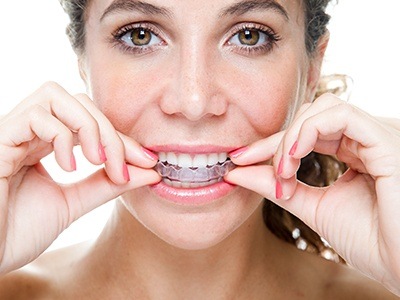 Woman putting Invisalign tray in her mouth