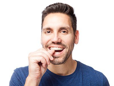 Man pushing in Invisalign tray on his teeth