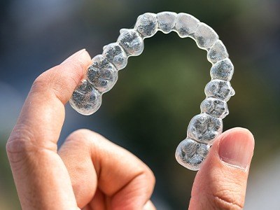 Hand holding an Invisalign aligner