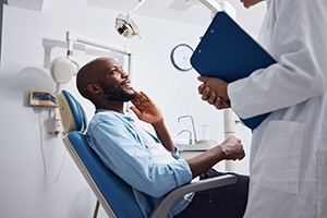 Man with glasses smiling while sitting in treatment chair