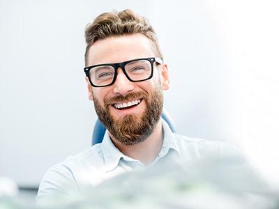 Man with glasses smiling in dental chair