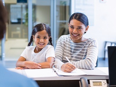 Mother and daughter at front desk of dental office