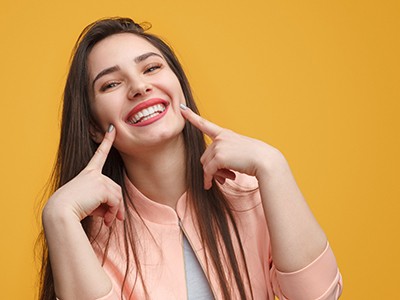 Young woman pointing to her smile