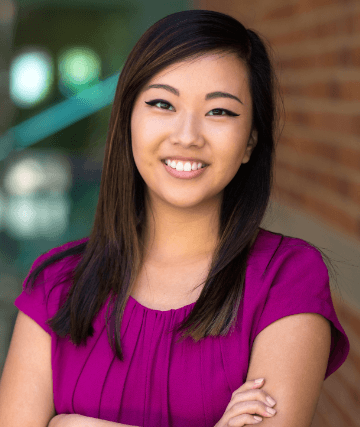 Woman in magenta blouse smiling with arms crossed