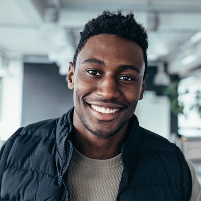 Man in black vest smiling in an office