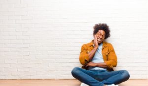 person sitting on the floor and holding their mouth in pain