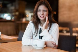 woman with toothache in coffeeshop 