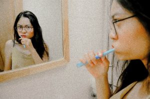 Woman looking in mirror brushing her teeth