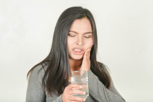 Woman with sensitive teeth drinking water