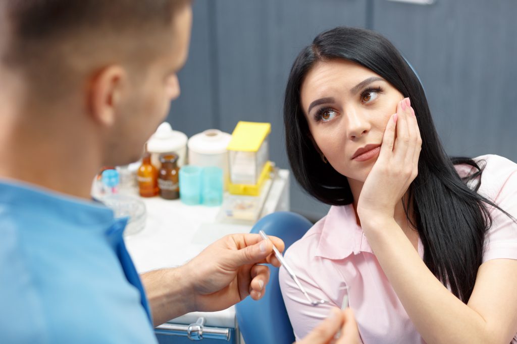 A woman holding her jaw because of impacted wisdom teeth