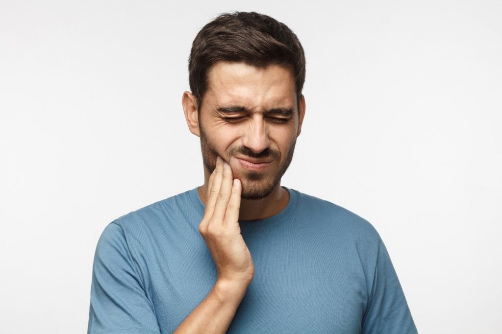 person with a dental emergency holding cheek