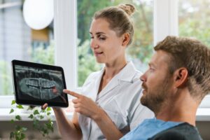 Dentist showing patient X-ray of wisdom teeth.